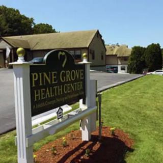 A sign for Pine Grove Health Center in front of a building and parking area.