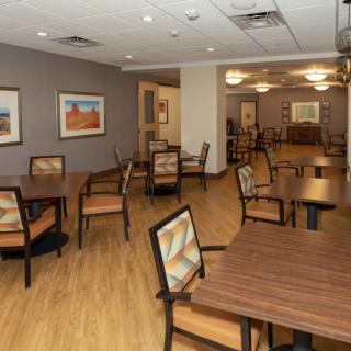 An empty dining room with wooden tables and chairs, featuring modern decor.
