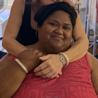 Two people smiling and hugging indoors.