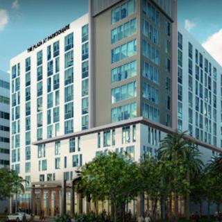 A modern hotel building with a sleek design and palm trees in an urban setting.