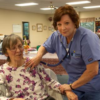 A nurse providing care to an elderly woman in a healthcare facility.