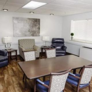 A cozy meeting room with a conference table, chairs, and comfortable armchairs.