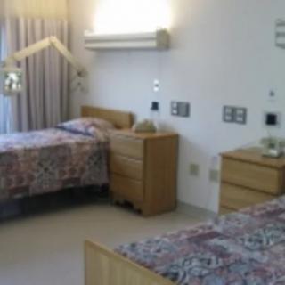 A room featuring twin beds with patterned bedspreads, dressers, and curtains.