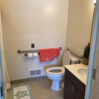 A small bathroom with a toilet, sink, and handrail.