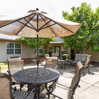 A cozy backyard patio with a table, chairs, and an umbrella.