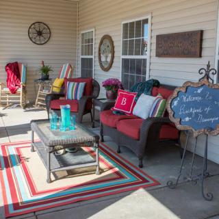 A cozy patio setup with colorful cushions, a rug, and outdoor decor for relaxing.