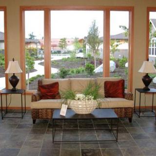 A cozy living room with a sofa, coffee table, and large windows providing an outdoor view.
