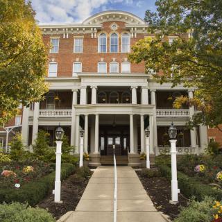 A historic hotel building with a grand entrance surrounded by manicured gardens.