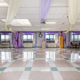 A spacious event hall featuring decorative drapes and large windows, creating a bright and inviting atmosphere.