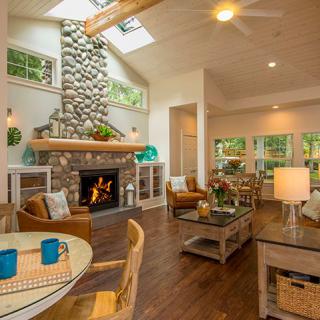 A cozy living room with a stone fireplace, modern decor, and a skylight illuminating the space.