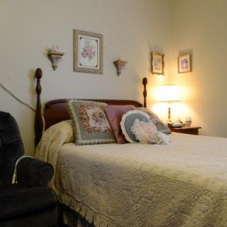 A cozy bedroom with a classic style, featuring a comfortable bed, decorative pillows, and warm lighting.