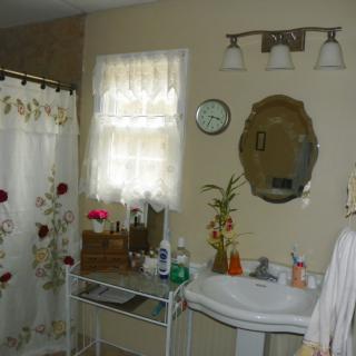 A cozy bathroom with floral decorations and a vintage mirror.