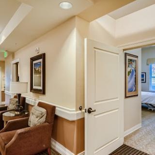 A cozy living room area leading to a private space, featuring comfortable chairs and wall art.