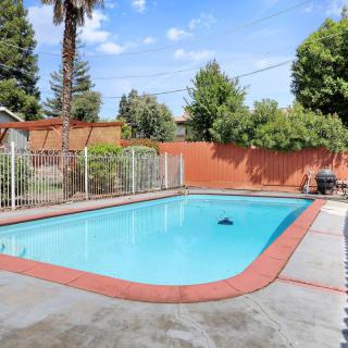 An inviting backyard swimming pool surrounded by a fence and greenery.