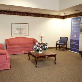 A cozy waiting area with pink sofas, a wooden coffee table, and a floral centerpiece.
