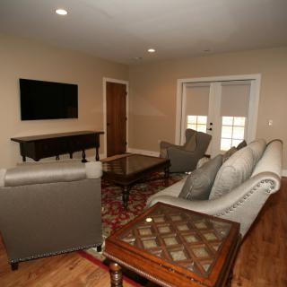 A cozy living room with modern furniture and a mounted television.