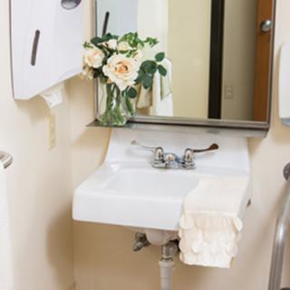 A bathroom sink with a mirror, decorated with a vase of flowers and a neatly folded towel.