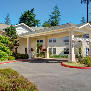 A sunny view of a hotel entrance surrounded by trees and landscaping.
