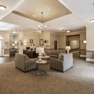 A spacious lobby area featuring comfortable sofas, elegant chandeliers, and a carpeted floor.