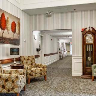 A modern hallway featuring patterned chairs, artwork, and a grandfather clock.