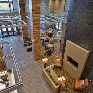 A modern lobby with a cozy seating area and fireplace, featuring wood accents and contemporary furniture.