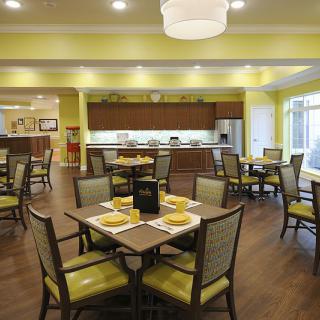 A modern dining area with neatly arranged tables and chairs, featuring bright lighting and contemporary decor.