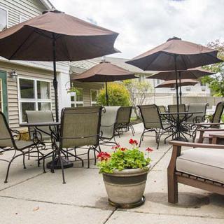 A cozy outdoor patio area with tables, chairs, and umbrellas, complemented by a potted flower arrangement.
