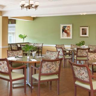A cozy dining area featuring floral-patterned chairs and a serene green wall, perfect for gatherings.