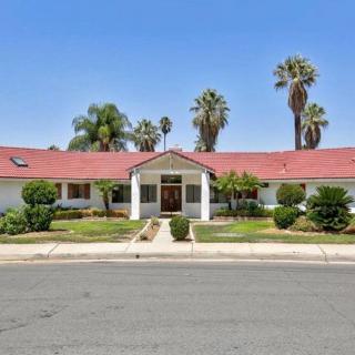 A suburban house with a red roof and palm trees in the yard.