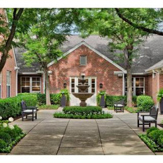 A serene courtyard featuring a beautiful fountain surrounded by well-maintained landscaping and outdoor seating.
