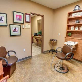 A cozy salon interior with styling chairs, decorative frames, and a wash sink.