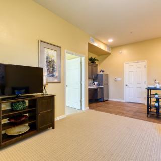 A cozy living room area with a television and a view into the kitchen.