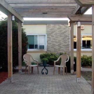 A backyard patio with a pergola, featuring two chairs and a small table.