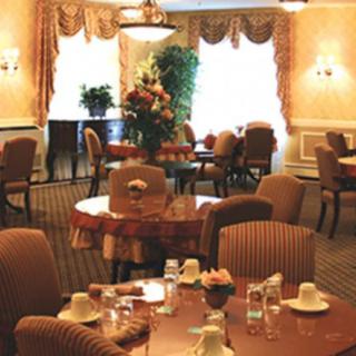 An elegant dining room setup with neatly arranged tables and chairs, featuring warm lighting and tasteful decor.