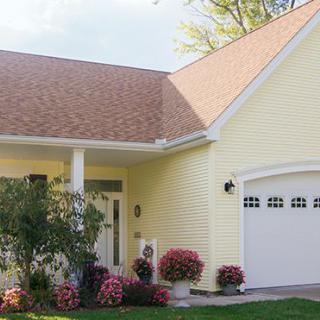 A charming yellow house with a garage and well-maintained garden.