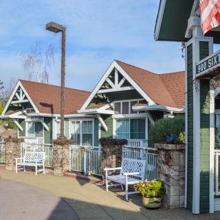 Charming cottages with benches and flowerpots lining a sunny pathway.