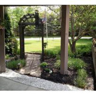 A charming garden with an archway leading to a pathway surrounded by lush greenery.