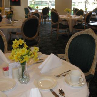 A beautifully set dining table in an elegant restaurant with daffodils as a centerpiece.