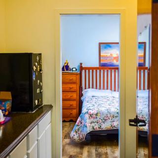 A cozy bedroom with a bed and wooden furniture, viewed from an adjacent room.