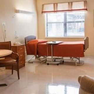 A well-lit hospital room with a bed and furniture.
