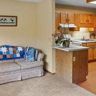 A cozy living room with a sofa and quilt, adjacent to a kitchen with wooden cabinets.
