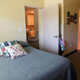 A cozy bedroom with a neatly made bed and an open door leading to another room.