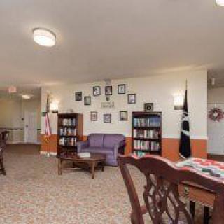 A cozy interior space with bookshelves, a sofa, tables, and flags.