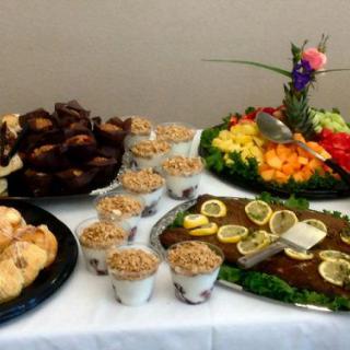 A buffet table featuring a variety of desserts including muffins, yogurt parfaits, and a colorful fruit platter.