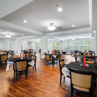 A spacious dining area with neatly arranged tables and chairs, featuring large windows and elegant lighting.