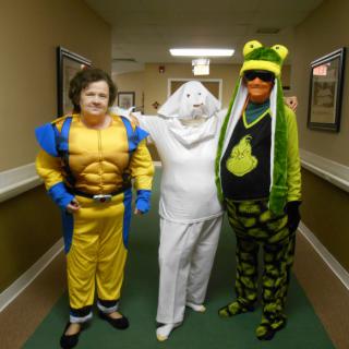 Three people in playful costumes pose together in a hallway.