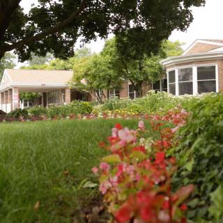 A charming house with a well-maintained garden featuring colorful flowers and lush greenery.
