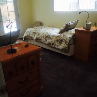 A cozy bedroom with a single bed, nightstand, and lamp.