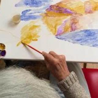An artist painting with watercolors on a canvas.