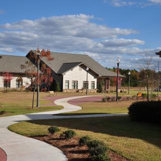 A scenic view of a building surrounded by landscaped lawns and a curved pathway under a partly cloudy sky.